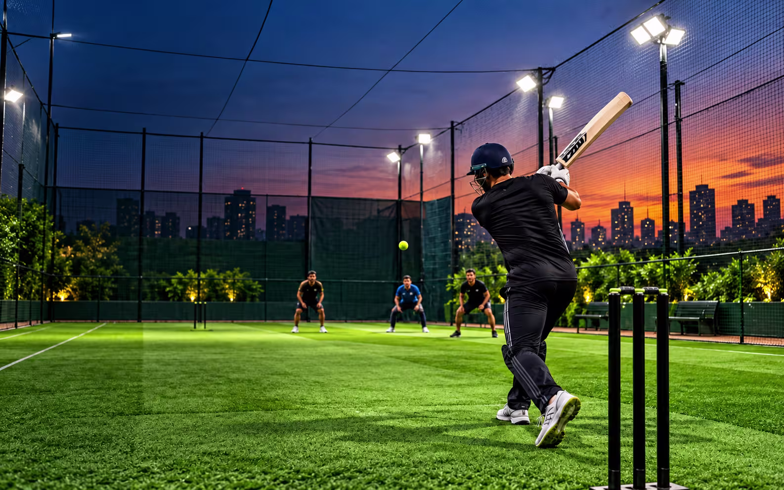 Floodlit cricket turf at dusk with players in the field
